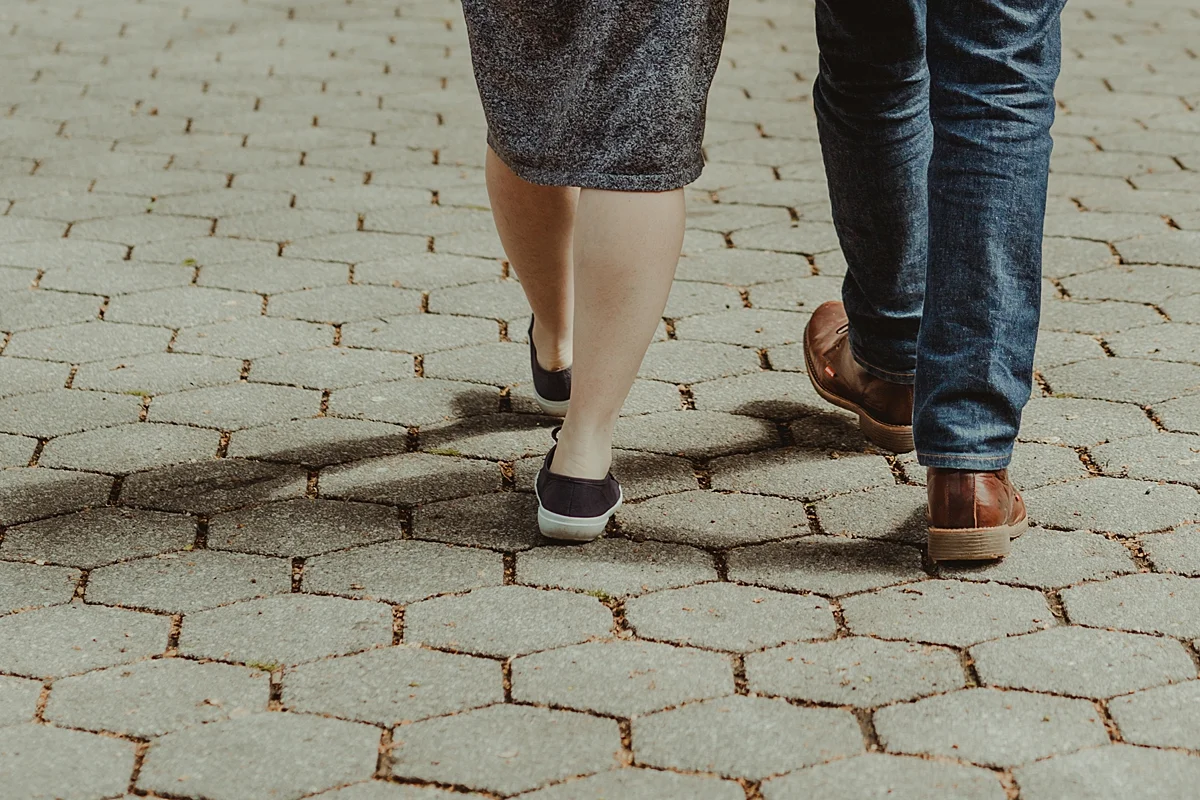 close up image of shoes of pregnant husband and wife walking away from the camera during outdoor maternity photo session. photo by nyc family and newborn photographer krystil mcdowall