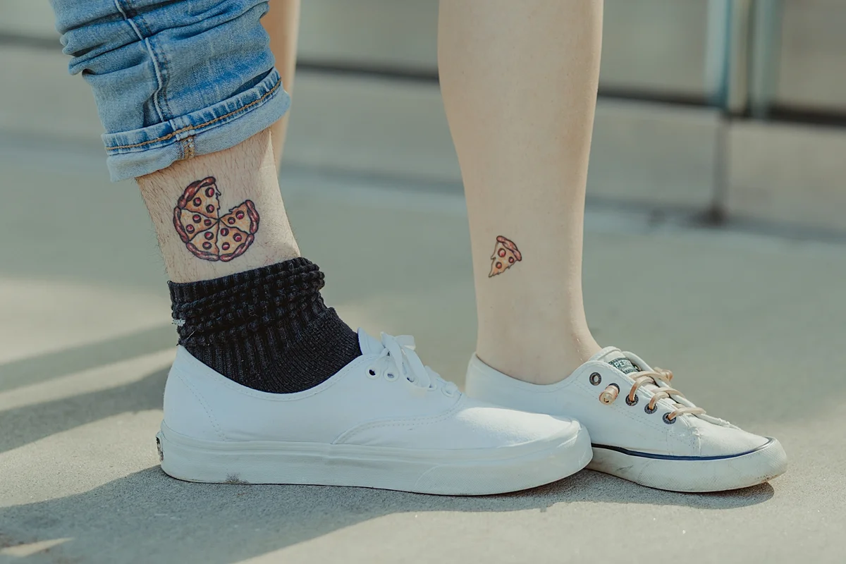 photo of pizza tatoos on legs of pregnant husband and wife taken during outdoor maternity photo session in brooklyn. image by krystil mcdowall photography