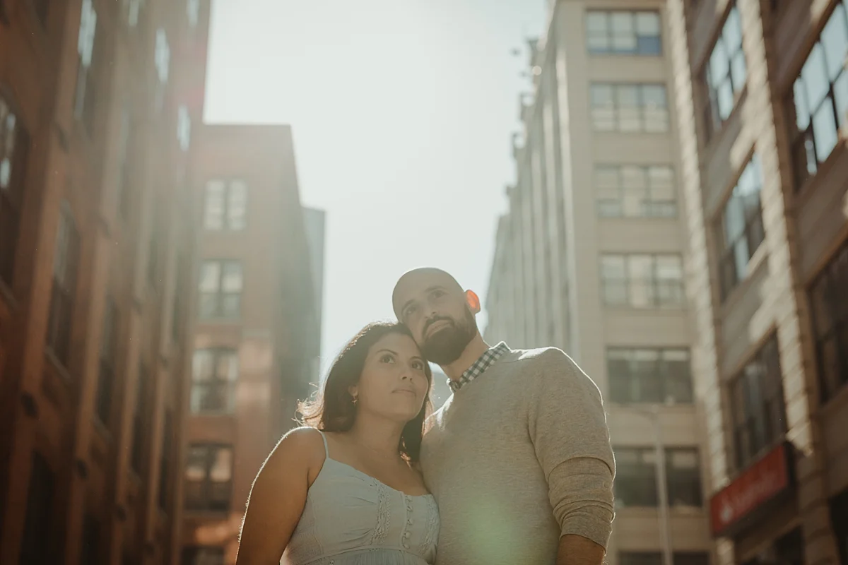 pregnant married couple stand in the middle of busy and bustling street with heads touching and looking out at the city streets for outdoor maternity photo session with orange county family photographer krystil mcdowall photography