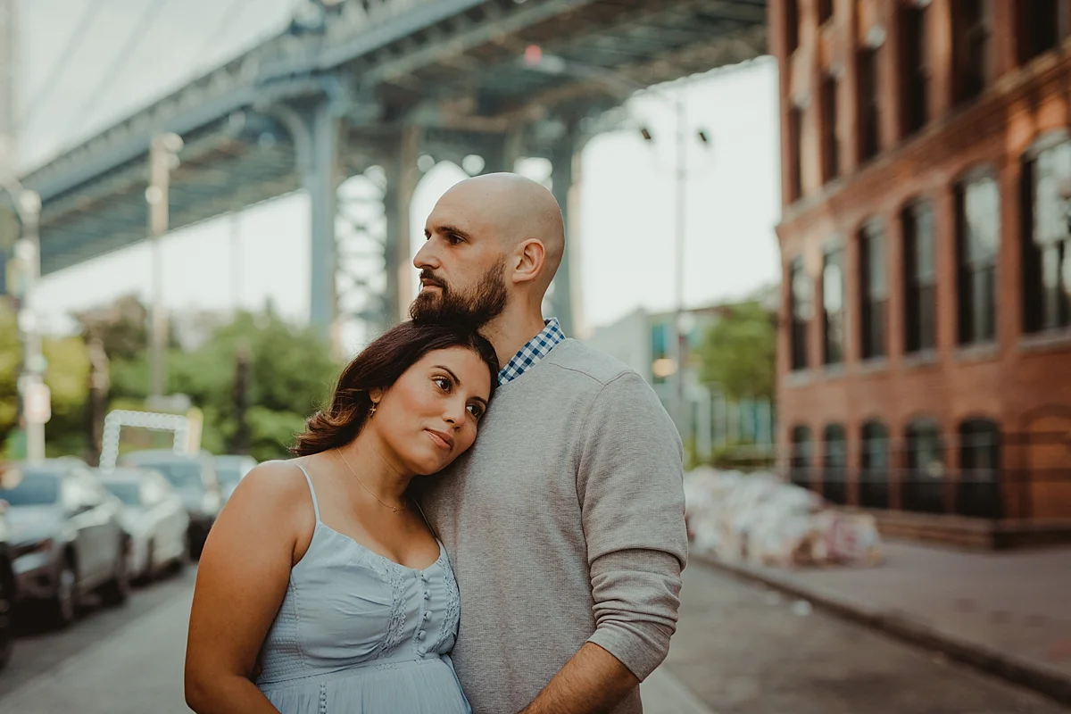 close up portrait of married couple standing in the middle of busy city street while husband holds wife's pregnant belly for outdoor maternity photo session with orange county family photographer krystil mcdowall photography