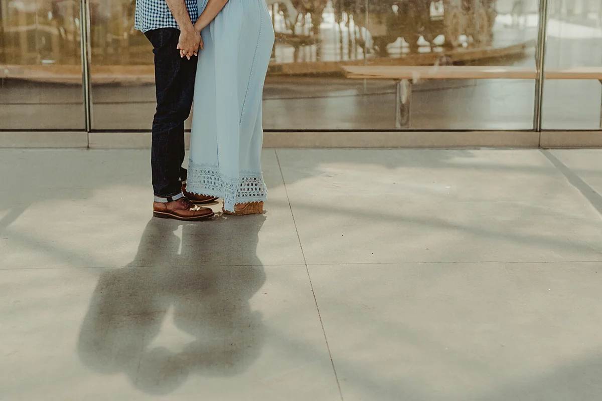 details photo of married couple holding hands in front of children'ts carousel while their dark shadows fall in front of the camera during lifestyle maternity photo session with orange county family photographer krystil mcdowall photography