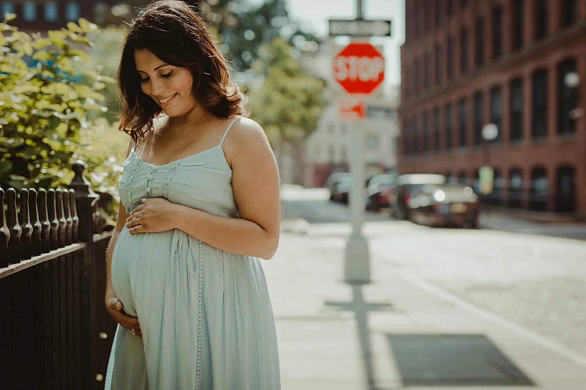 portrait of expecting mom in beautiful light blue maternity dress holding her big and beautiful pregnant belly during outdoor maternity photo session with orange county family photographer krystil mcdowall