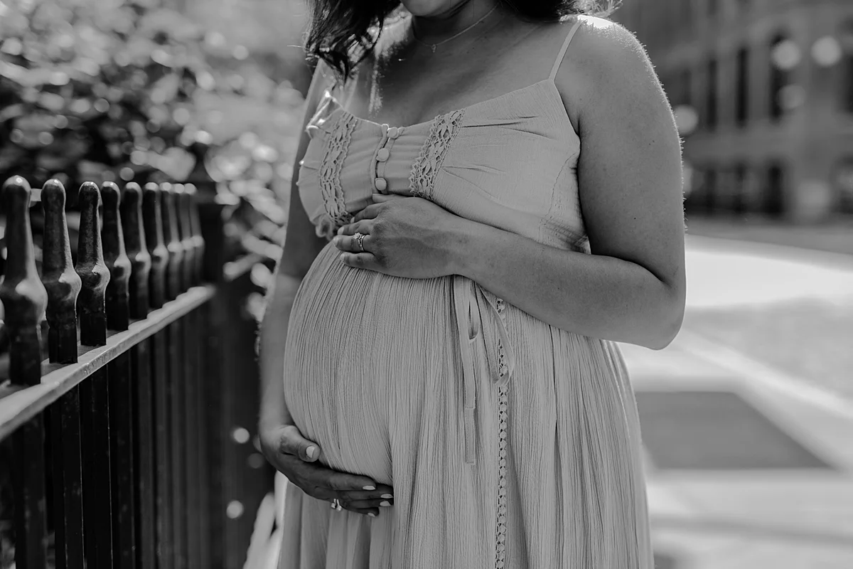black and white portrait of expecting mom while she she holds her big and beautiful pregnant belly during outdoor maternity photo session with orange county family photographer krystil mcdowall