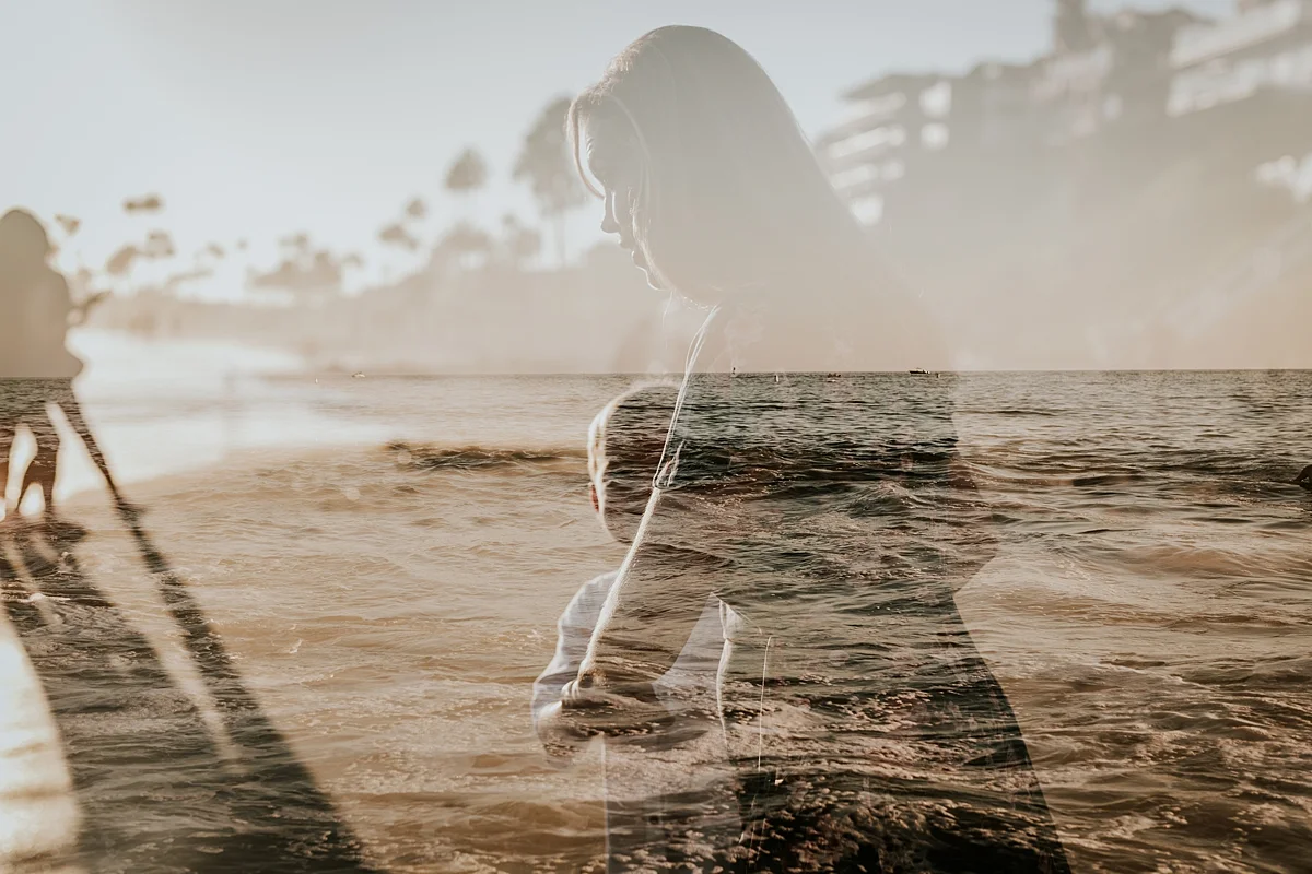 orange county family photographer. double exposure photo of mom and her son walking into the waves at Corona del Mar State Beach