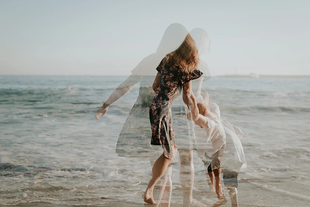orange county family photographer double exposure photo of mom and son running into the ocean at corona del mar state beach california