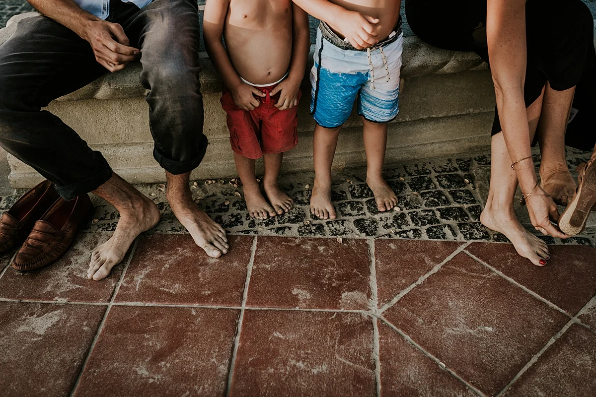 Orange County family photographer. candid photo of family of four washing the sand off their feet before heading up to the pier