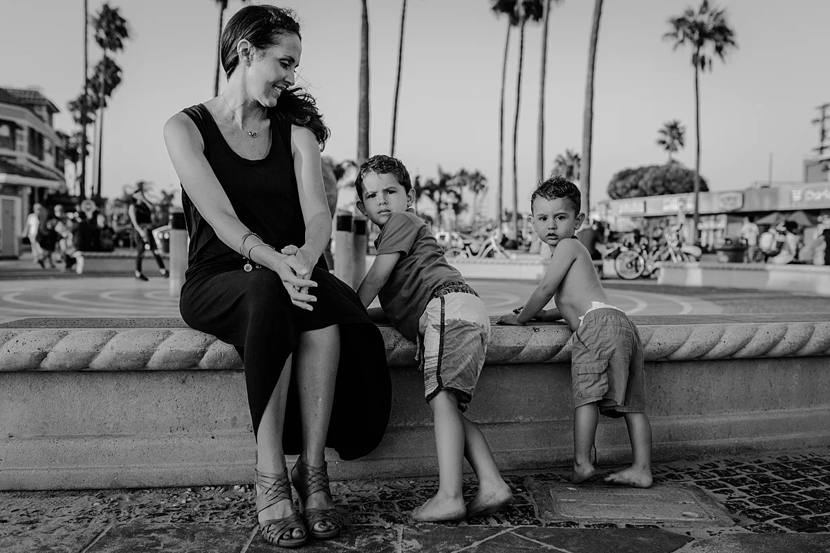 Orange County family photographer. photo of mom and her two boys standing on the streets of Huntington Beach during outdoor family photo session at Huntington Beach Pier California with Krystil McDowall Photography