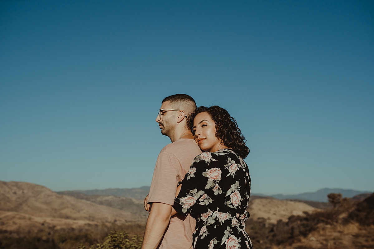Orange County family photographer. candid photo of couple embracing atop the hills at Irvine Regional Park Orange County