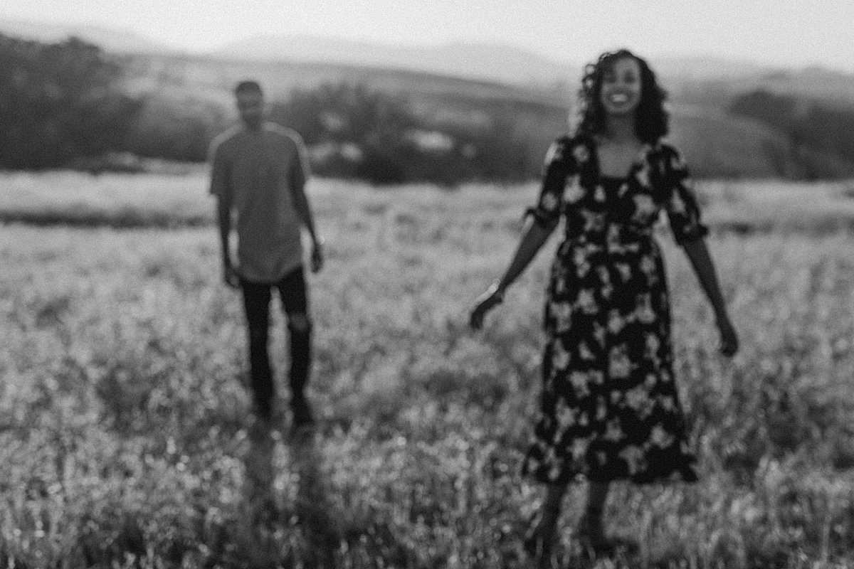 Orange County family photographer. blurred black and white photo of married couple walking through fields at couple's photo session at Irvine Regional Park