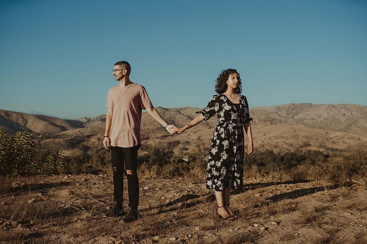 orange county family photographer. photo of married couple standing arms stretched amongst the mountains in Irvine Regional Park Orange County