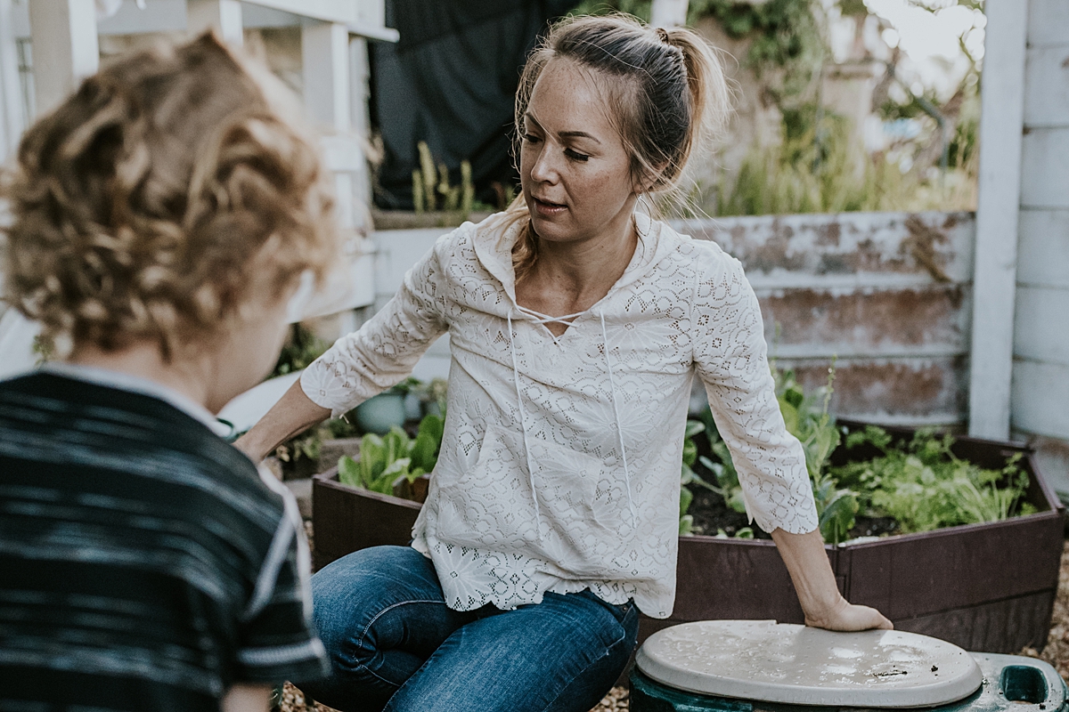 Orange County family photographer. Photo of mother getting hose ready to water plants during documentary photo session with Krystil McDowall Photography