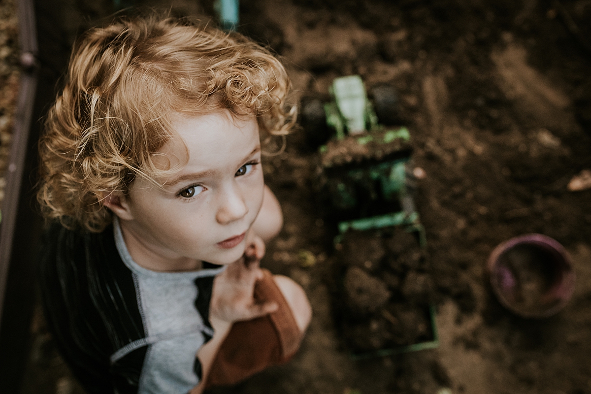Orange County family photographer. Photo of young boy sitting in his front yard garden during documentary photo session with Krystil McDowall Photography