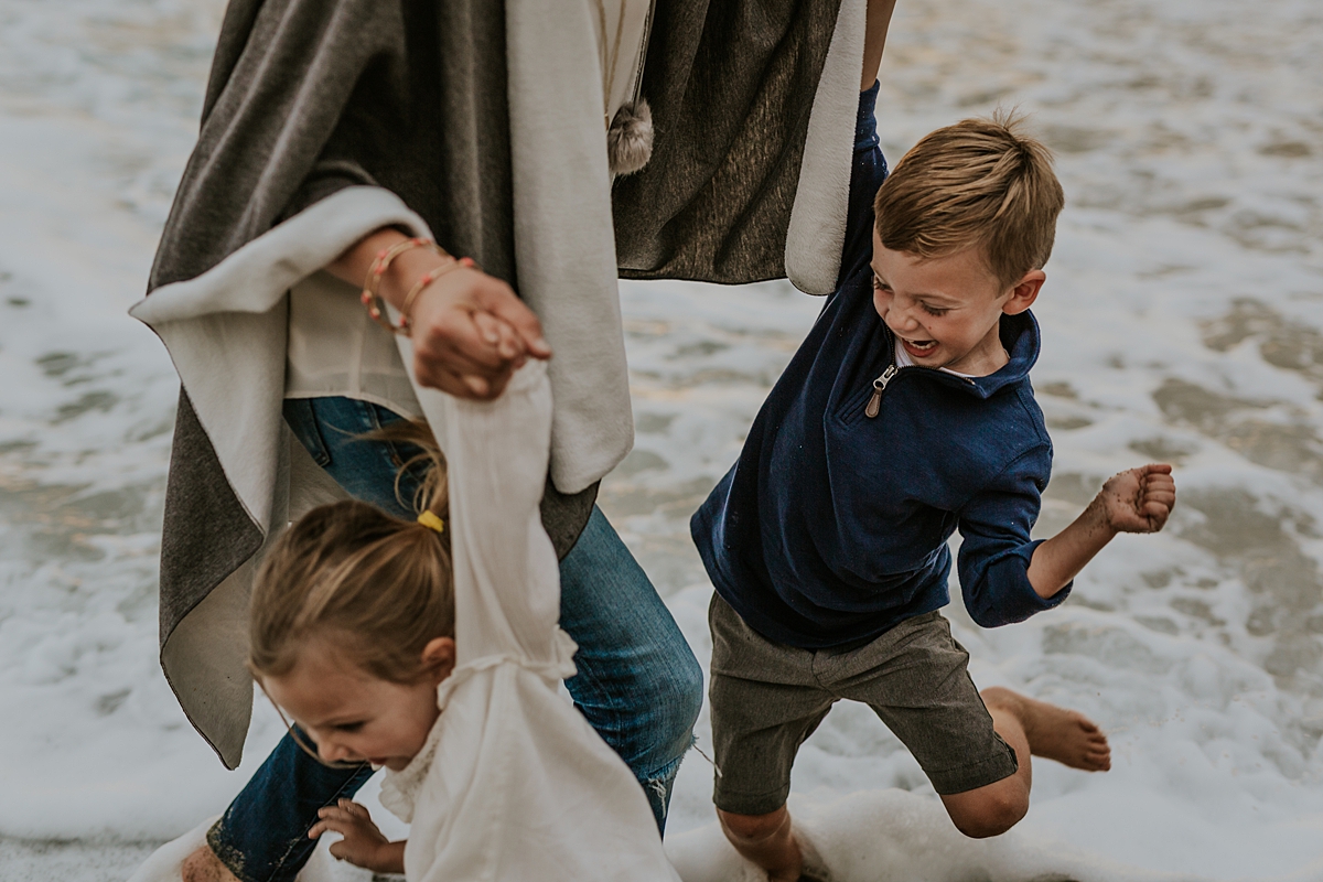 Orange County family photographer. Mom hustles her son and daughter out of the ocean at Table Rock Beach Laguna Beach during photo session with Krystil McDowall Photography
