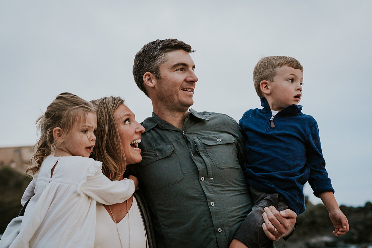 Orange County family photographer. family of four looks out into the sunset at Table Rock Beach Laguna Beach during photo session with Krystil McDowall Photography