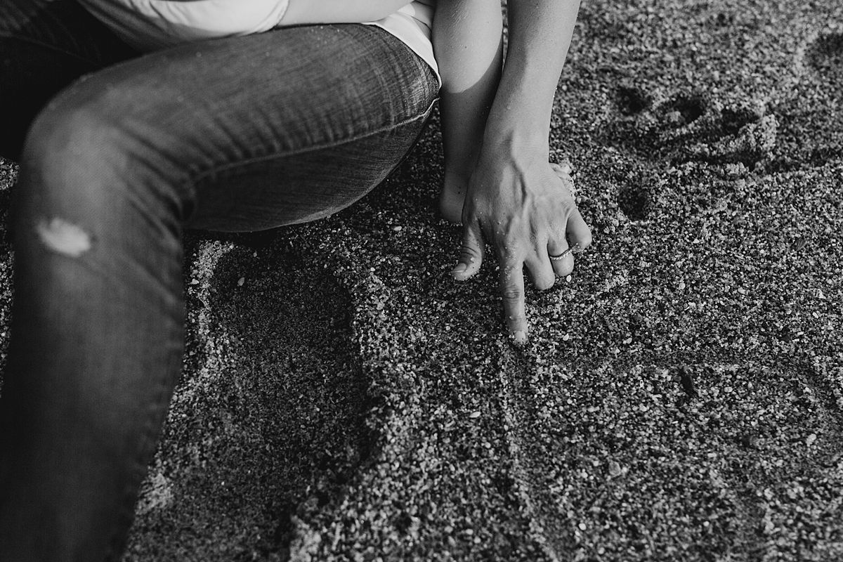Orange County family photographer. Photo of mom drawing love heart in the sand at Table Rock Beach Laguna Beach during photo session with Krystil McDowall Photography