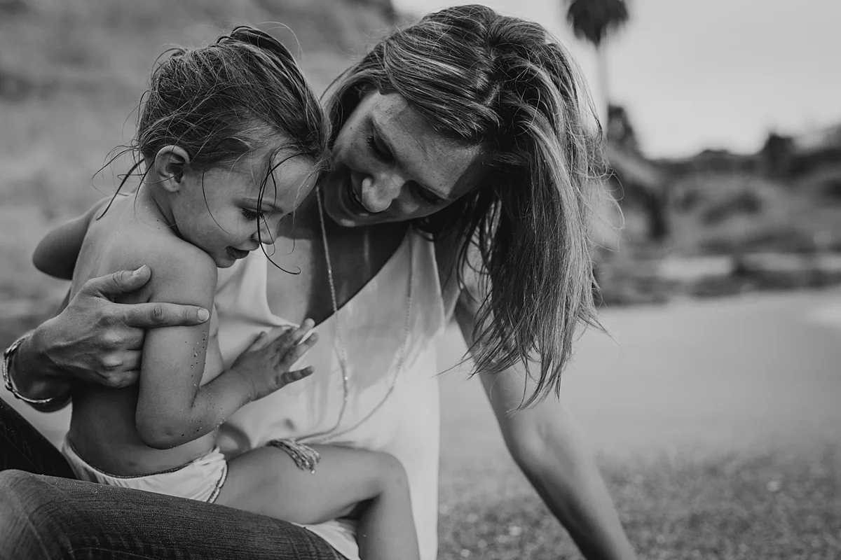 Orange County family photographer. Photo of mom and daughter sitting in the sand at Table Rock Beach Laguna Beach during photo session with Krystil McDowall Photography