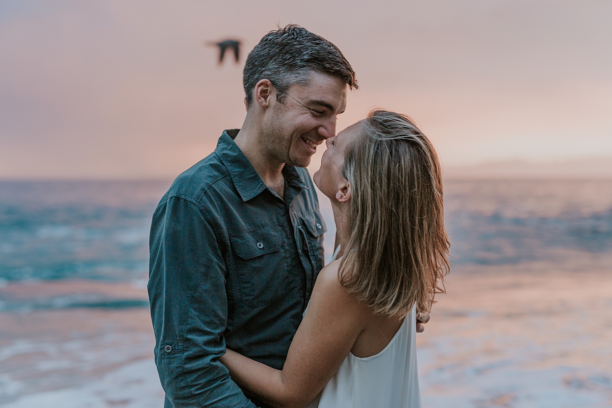 Orange County family photographer. Photo of mom and dad embracing as the sunsets at Table Rock Beach Laguna Beach during photo session with Krystil McDowall Photography