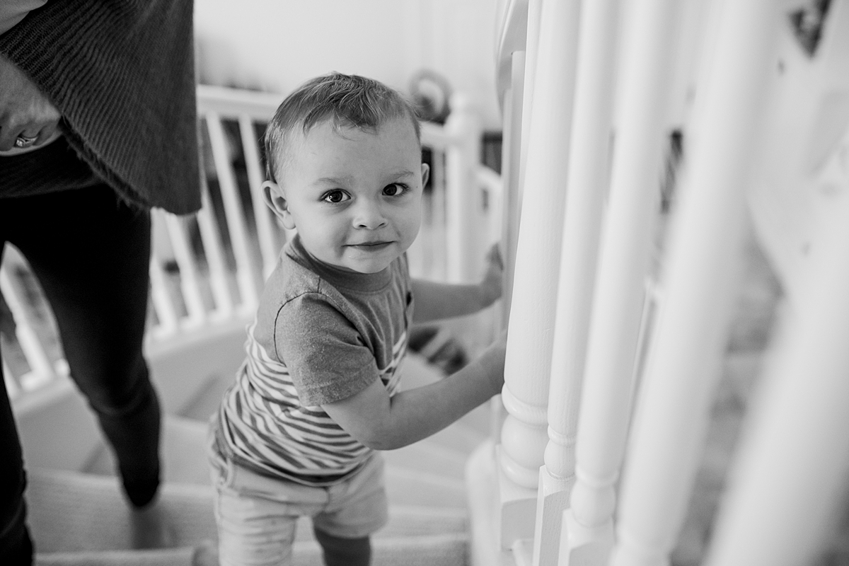 Orange County family photographer. photo of older brother coming up the stairs during in-home newborn session with Krystil McDowall Photography