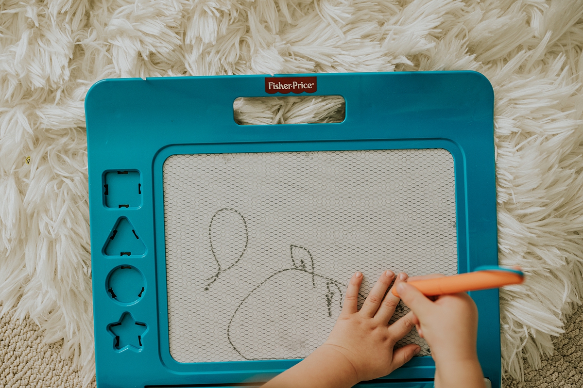 Orange County family photographer. Close up photo of boy tracing his hand with his doodle pro in his room