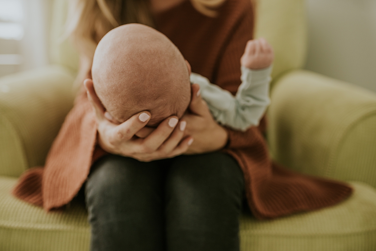Orange County family photographer. Close up photo of mom holding her newborn son's head gently in her hands during in-home newborn session
