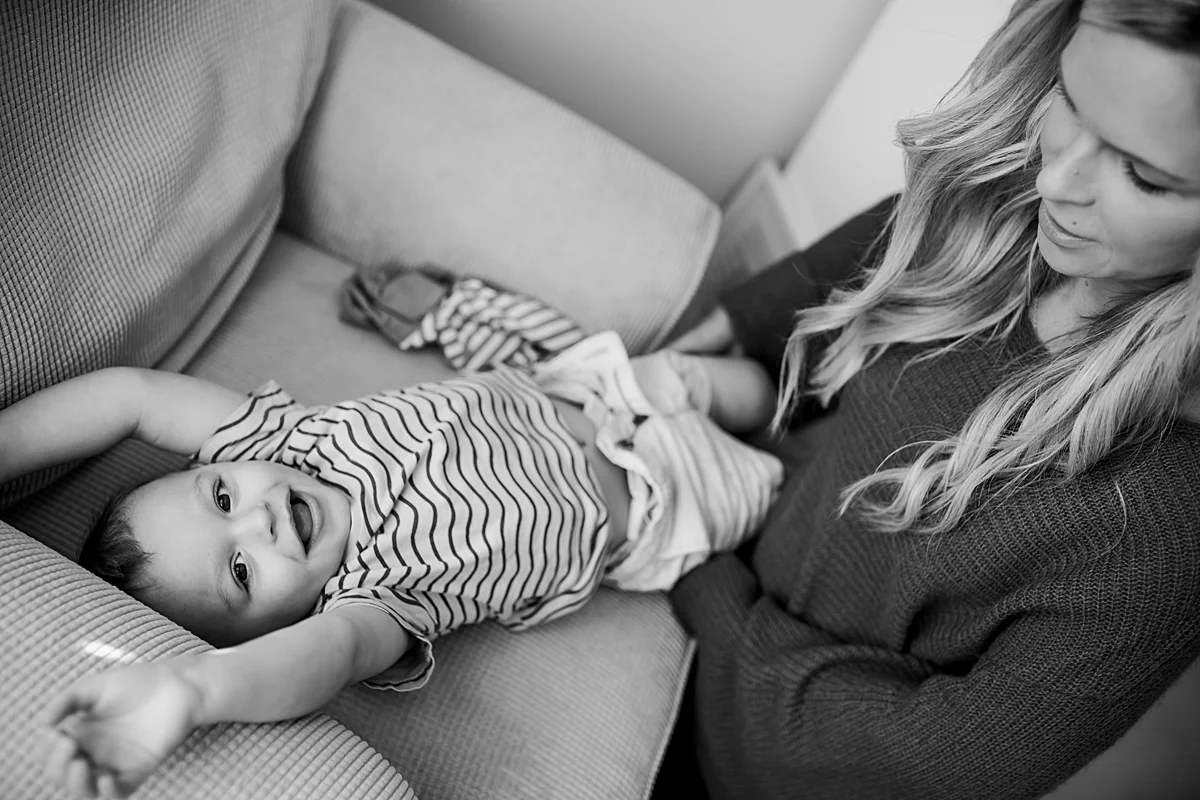 Orange County family photographer. Photo of mom trying to change her son's clothes after the got dirty during in home newborn photo session