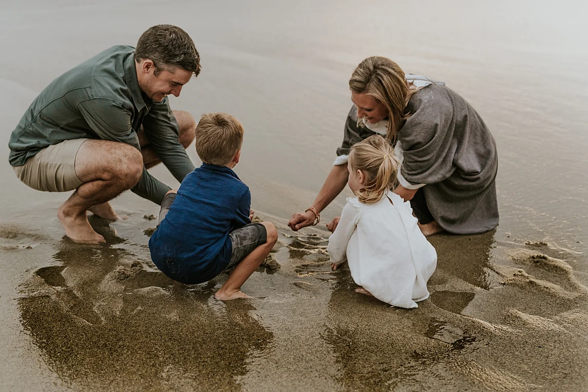 Orange County family photographer. Photo of family of four playing in the wet sand during outdoor family photo session at Table Rock Beach Laguna Beach