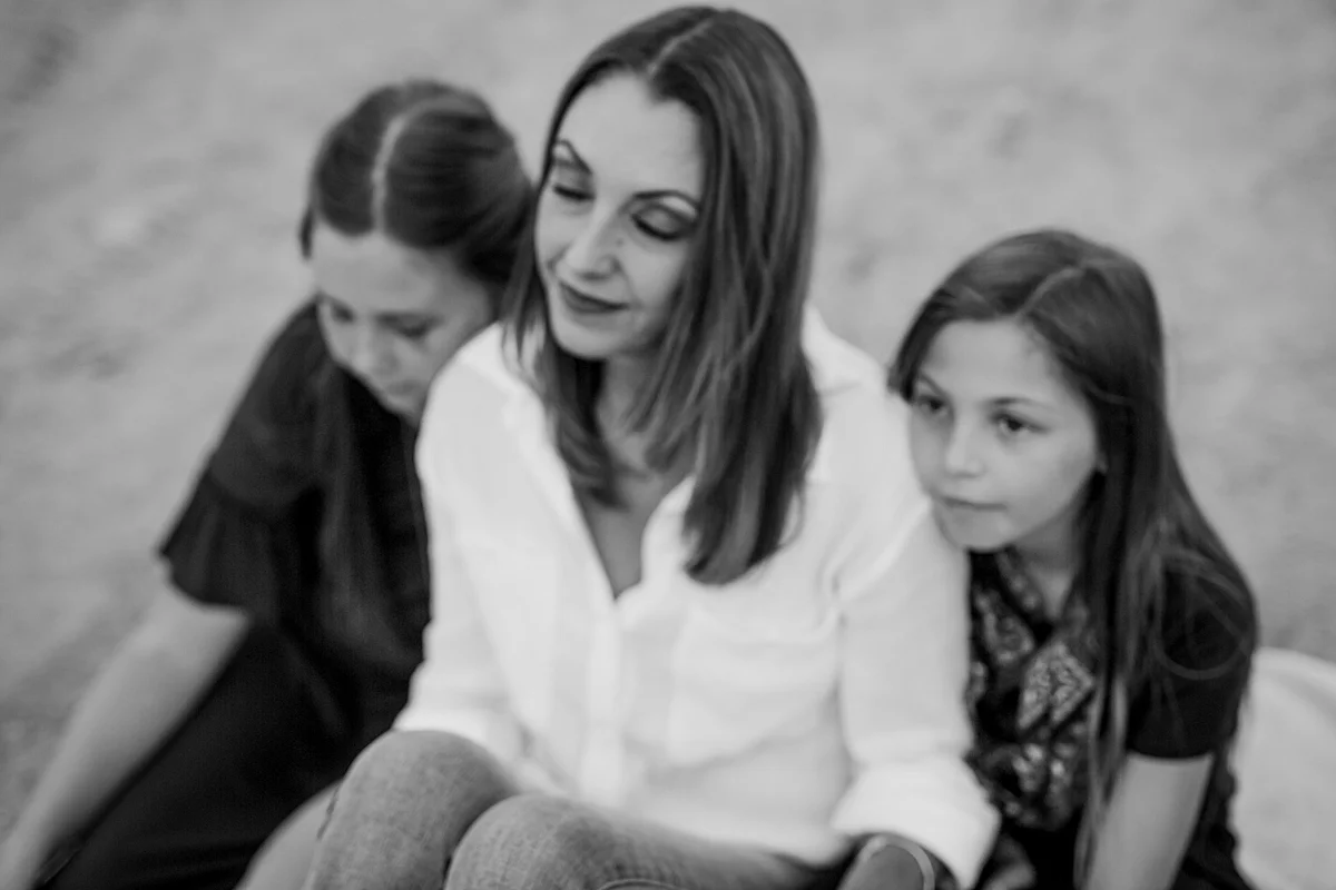 Orange County family photographer. Candid photo of mom resting with her two daughters during family photo session at top of the world laguna beach