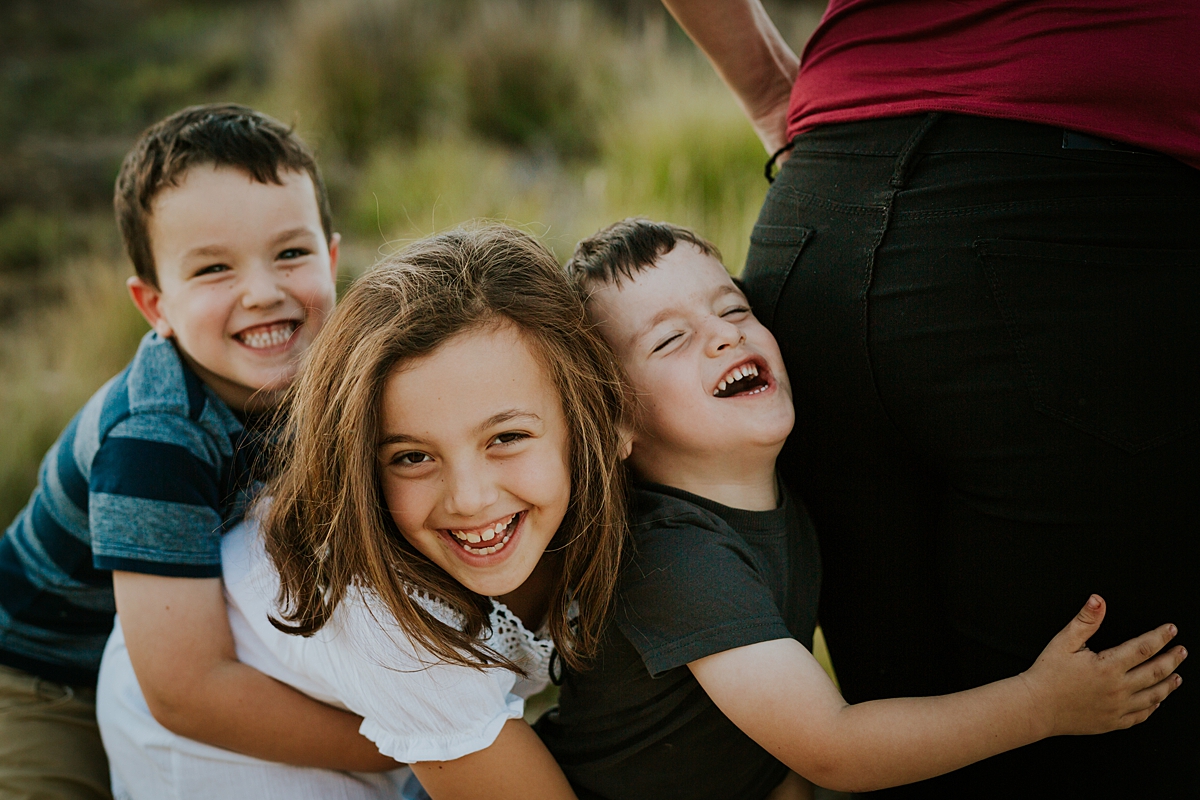 Orange County family photographer. Candid photo of brothers and sister laughing and mucking around at family photo shoot at Quail Hill