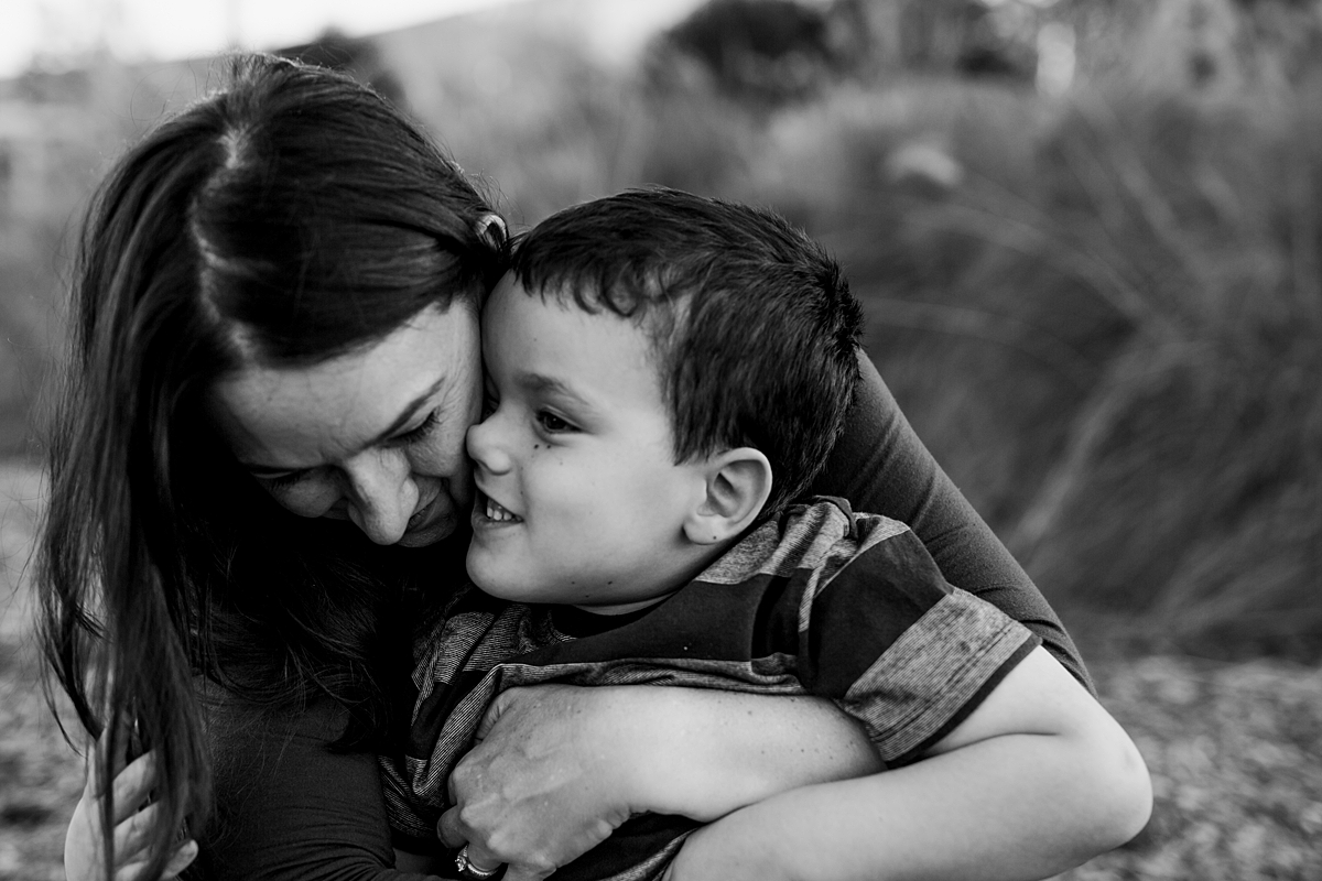 Orange County family photographer. Beautiful candid black and white photo of boy pressing his nose up against his mom's cheek during family photo shoot at Quail Hill