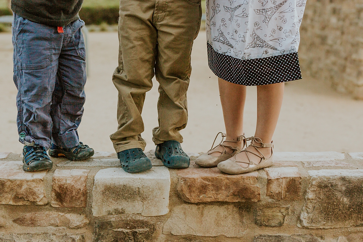Orange County family photographer. Photo of sibling feet as they stand on a stone wall during family photo shoot at Quail Hill with Krystil McDowall