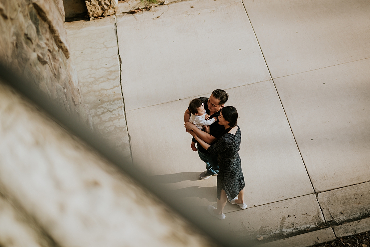Orange County family photographer. Photo of mom and dad throwing their one year old daughter in the air at bridge opening during outdoor family photo session at Jeffrey Open Space Trail Irvine