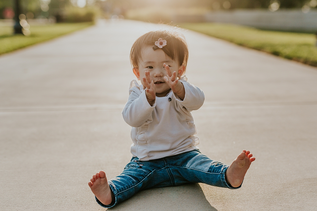 Orange County family photographer. Portrait of young girl clapping her hands while sitting on path at Jeffrey Open Space Trail Irvine