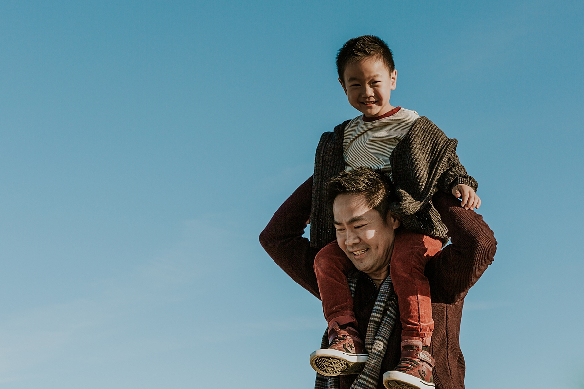 Orange County family photographer. Dad gives his son a fun shoulder ride at Top of the World Laguna Beach during outdoor family photo session
