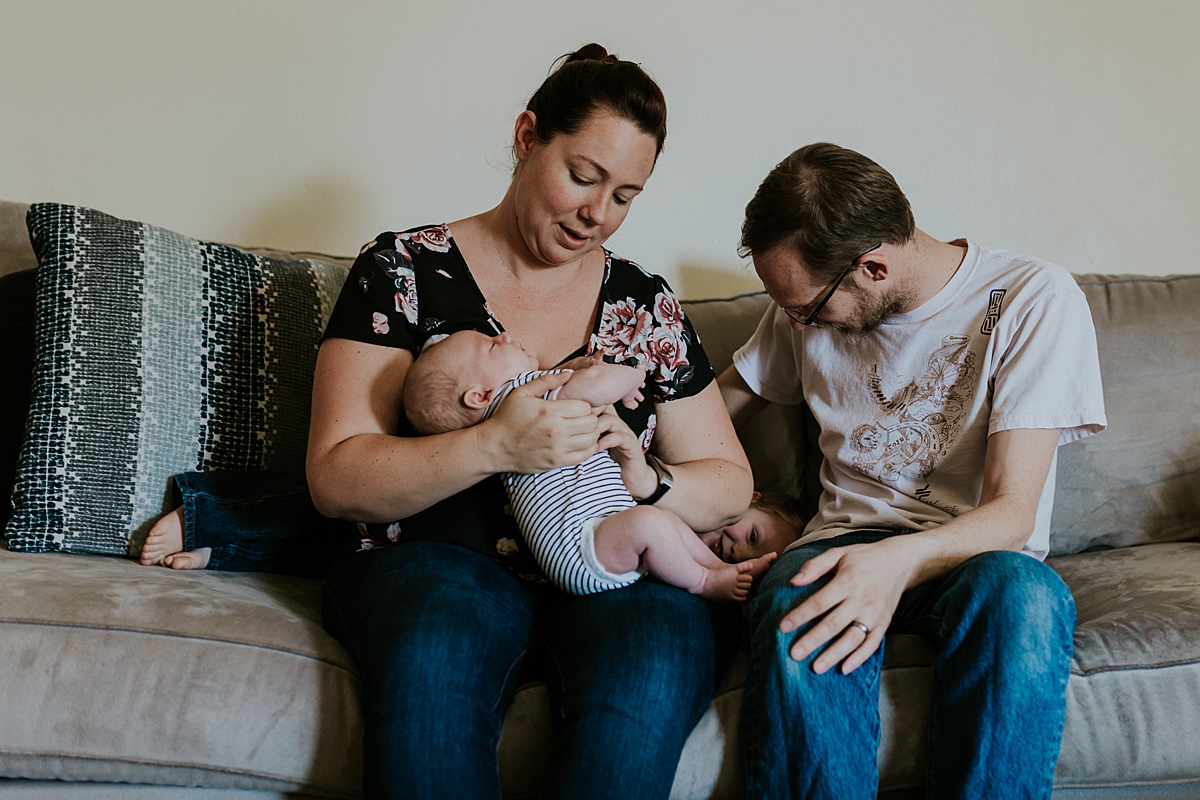 Orange County family photographer. Candid photo of mom, dad, big brother and newborn son sitting on their couch during in home newborn session with Krystil McDowall Photography