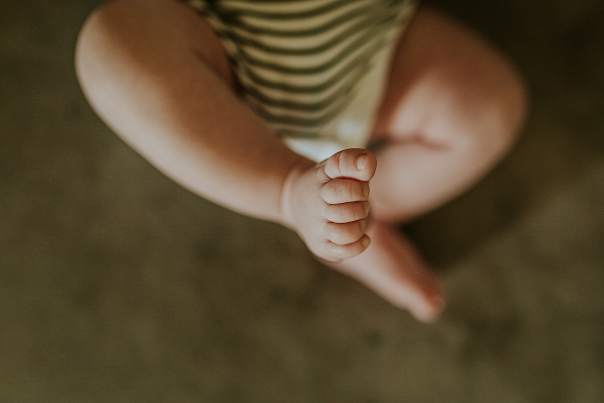 Orange County family photographer. Photo of newborn son's feet as he lays on his couch looking at the camera during in home newborn session with Krystil McDowall Photography