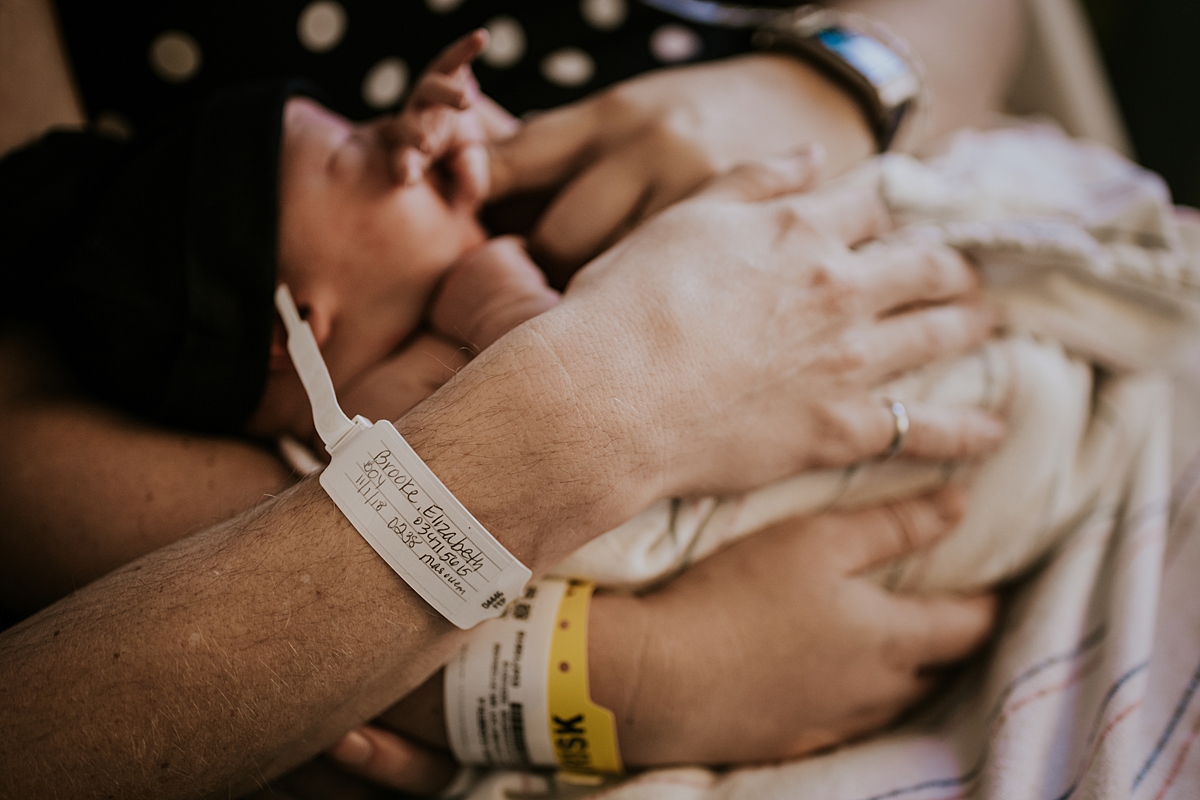 Orange County family photographer. Photo of mom and dad's hospital wrist bands as they hold their two day old newborn baby during fresh 48 session with Krystil McDowall Photography