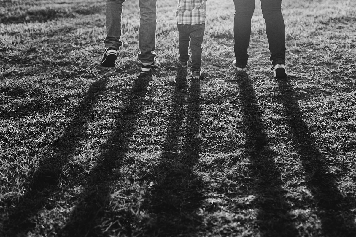 Orange County family photographer. Photo of shadows of mom, dad and toddler standing in the grass at sunset during maternity photo shoot at Irvine Regional Park