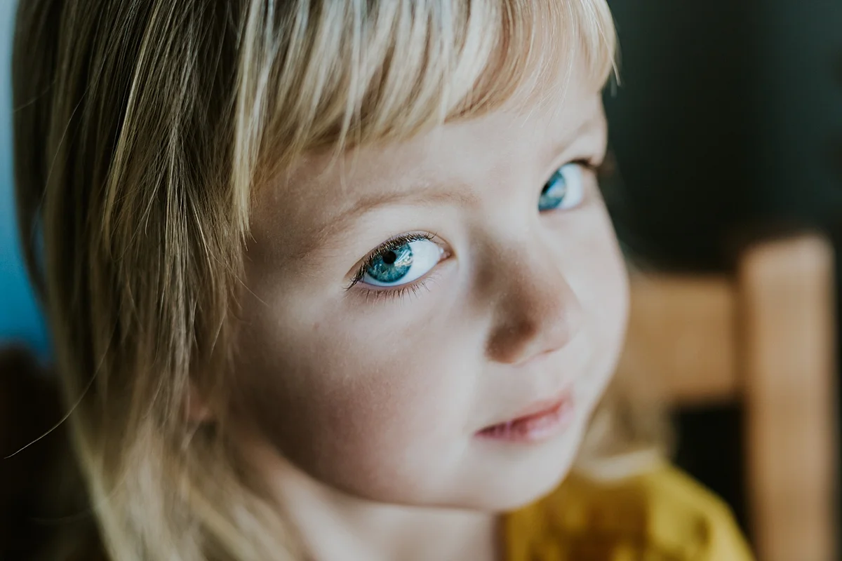 Orange County family photographer. Portrait of beautiful four year old girl in mustard dress and big blue eyes taken during in home family session in Long Beach