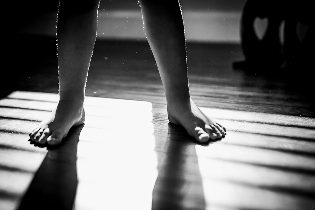 Orange County family photographer. Backlit photo of young girl's barefeet as she plays in the sun shining in her room taken during in home family session in Long Beach