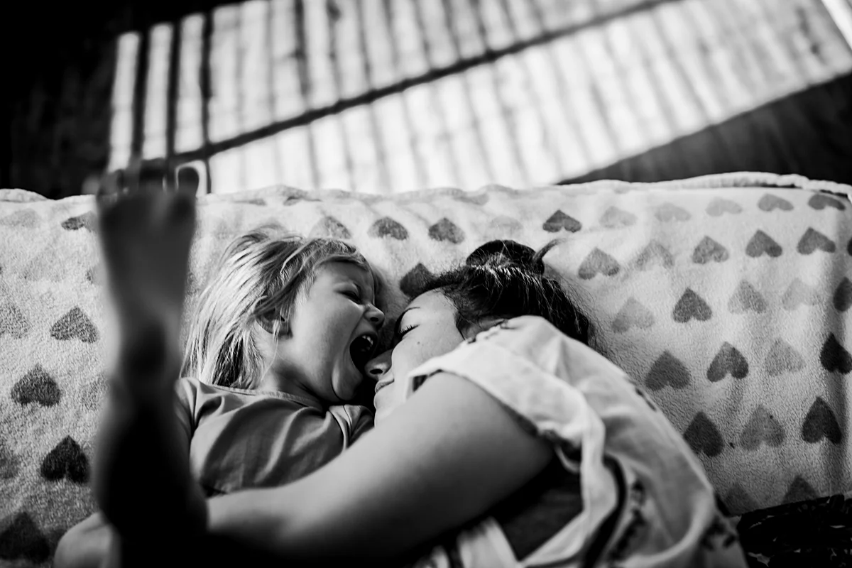 Orange County family photographer. Candid photo of mom and daughter playing on daughter's bed during in home family photo session in Long Beach, CA