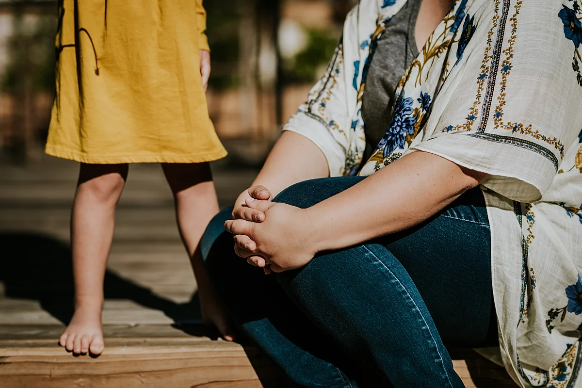 Orange County family photographer. Details photo of mom and daughter's legs as they sit in their front yard during in home family photo session in Long Beach, CA