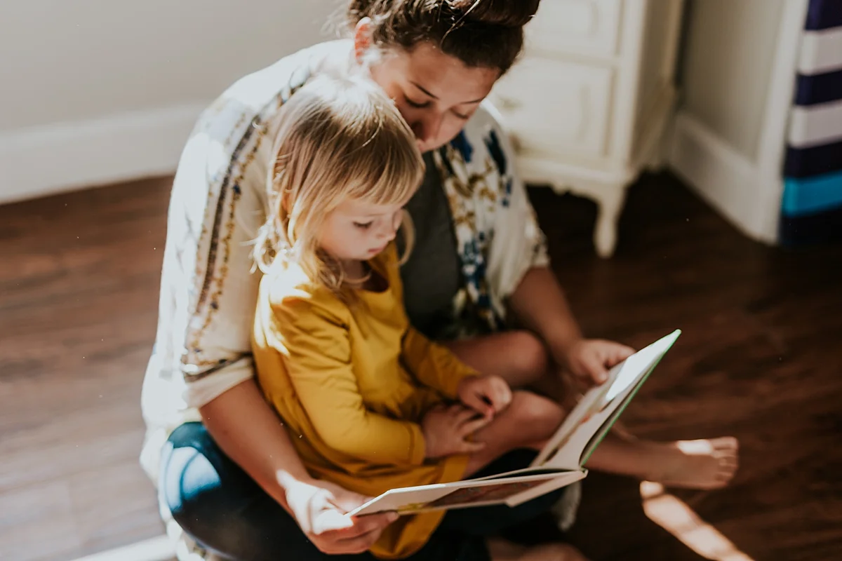Orange County family photographer. Photo of mom and daughter reading a book together during in home family photo session in Long Beach, CA