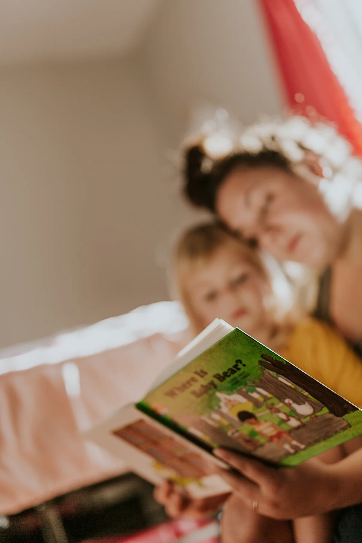 Orange County family photographer. Photo of mom and daughter reading a bear book in daughter's bedroom during in home family photo session in Long Beach, CA