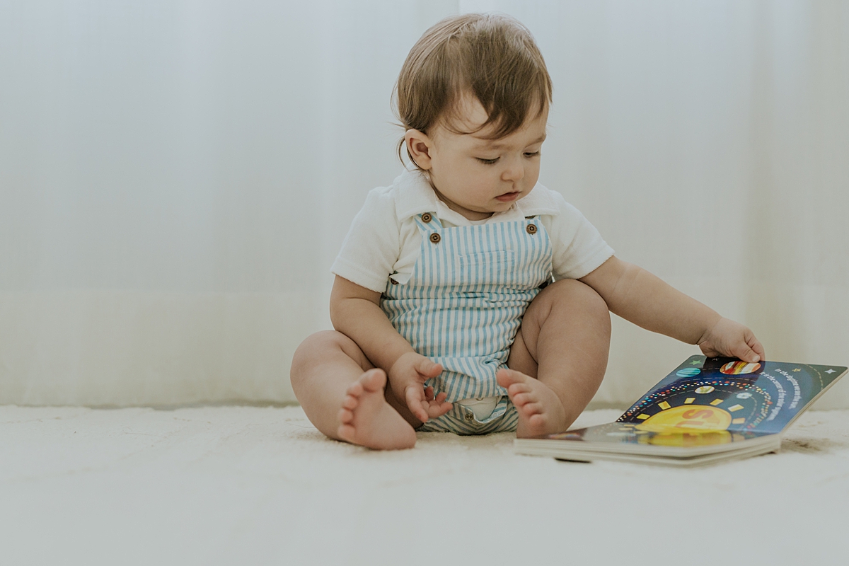 Orange County family photographer. Photo of one year old boy reading his book in his room during in family photo session in Irvine CA