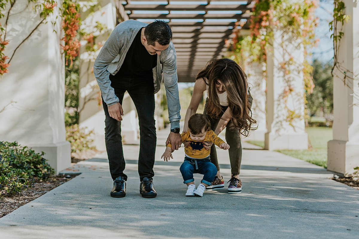 Orange County family photographer. Candid photo of mom, dad and one year old boy walking at local Irvine park during family photo session in Irvine CA