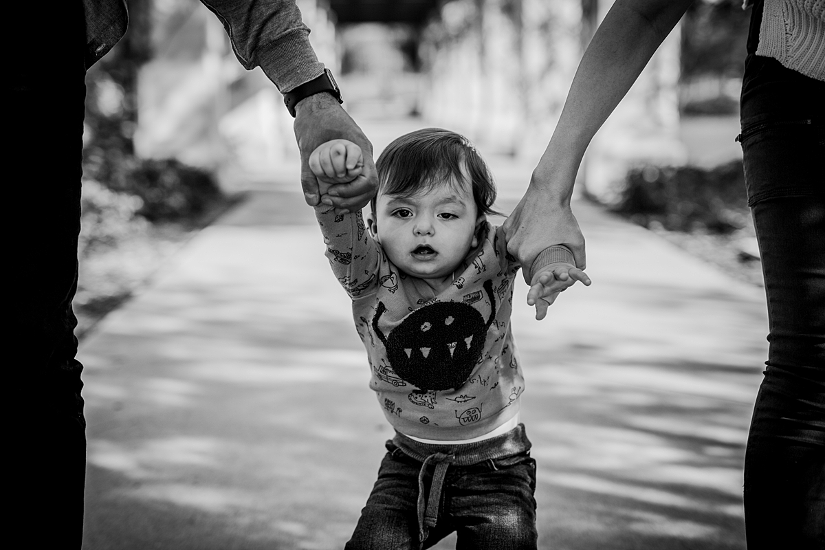 Orange County family photographer. Candid photo of son walking hand-in-hand with his parents at local Irvine park during family photo session in Irvine CA