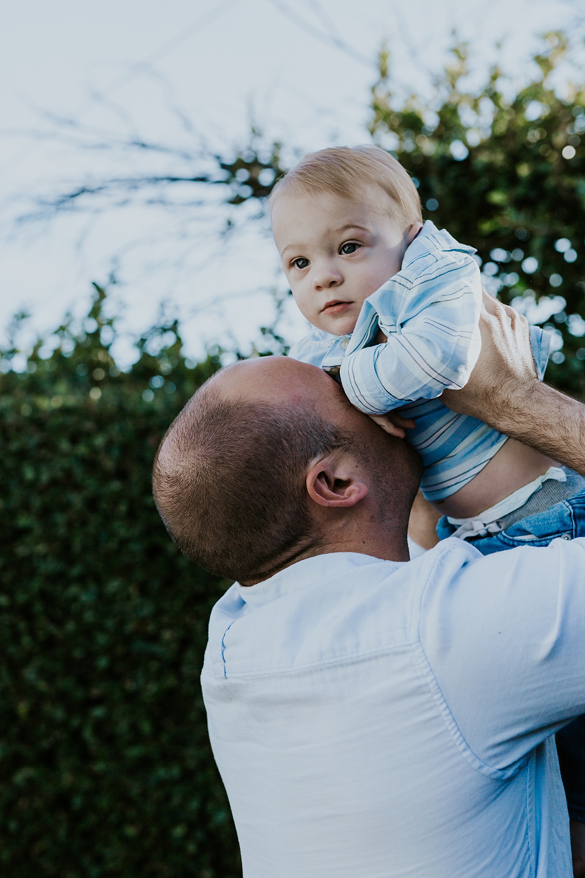 Orange County family photographer. photo of dad snuggling his super cute blonde haired son in their backyard during in home family photo shoot in Huntington Beach