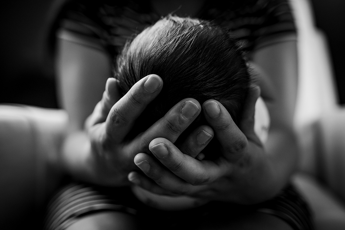 Orange County family photographer. black and white photo of mom's hands as she cradles her newborn son's head during newborn photo shoot in Lake Forrest Orange County