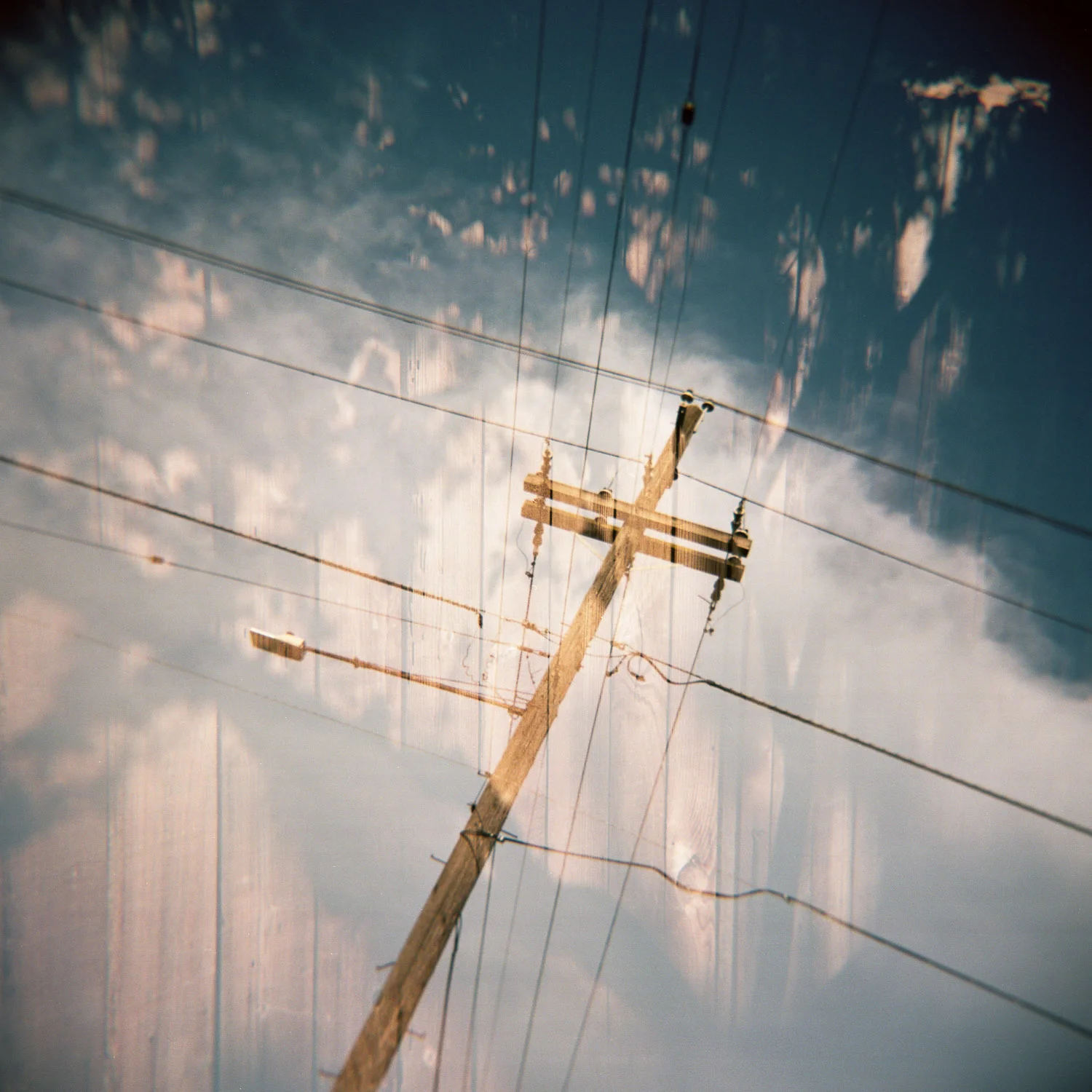 Double exposure Holga photo of power lines and a fence
