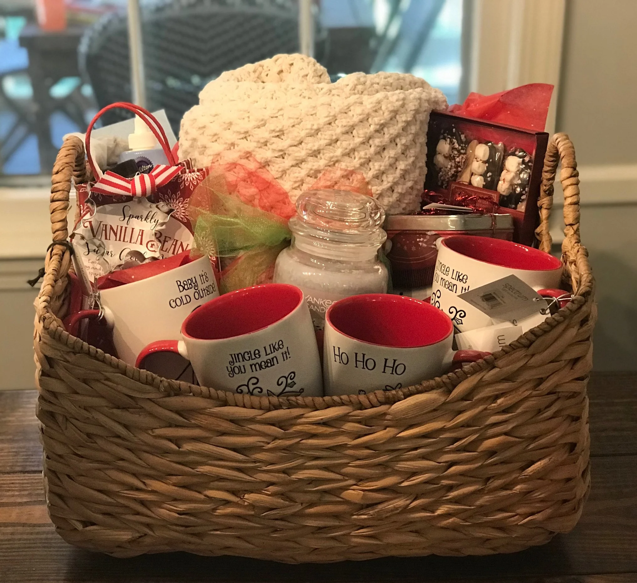 CHRISTMAS MOVIE NIGHT BASKET Snuggle up by the fire in this warm blanket and settle in for a fun family movie night. Included with the blanket are mugs and accessories for hot chocolate, popcorn, cookie mix and decorations, a candle and the movie "Polar Express". DONOR: 1st Grade Classes VALUE: $105